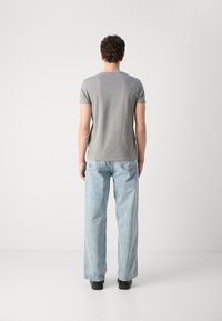 Γκρι βαμβακερό t-shirt κοντομάνικο συνδυασμένο με ανοιχτό μπλε παντελόνι wide-leg. Το σύνολο έχει casual εφαρμογή και μίνιμαλ λεπτομέρειες.