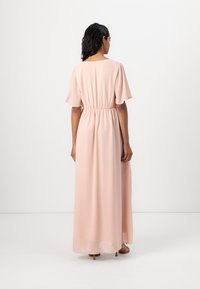 Rochie lungă, roz, dintr-un material mătăsos, cu mâneci scurte și vaporoase și talie strânsă. Design minimalist cu o siluetă fluidă, care atinge gleznele.