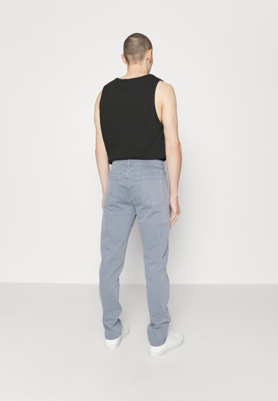 Gray trousers with a straight-leg design, made from cotton. The outfit is paired with a black sleeveless top and white sneakers.