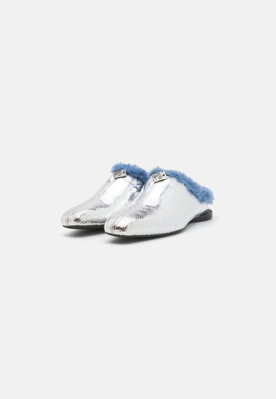 Sølvmetalliske slip-on sko med teksturert overdel, blå kunstpelsdetalj, og sølvuttak foran. Flat svart yttersåle.