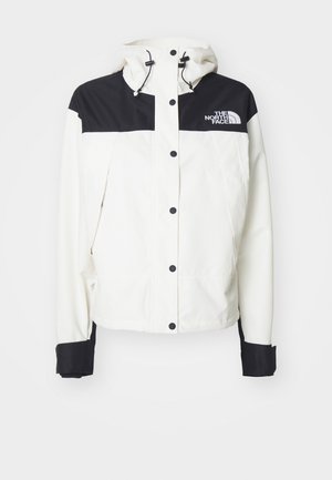 Witte jas met een zwart boven gedeelte en schouders, voorzien van een capuchon, drukknoopsluiting en zwarte manchetten. Het logo van The North Face staat op de borst.
