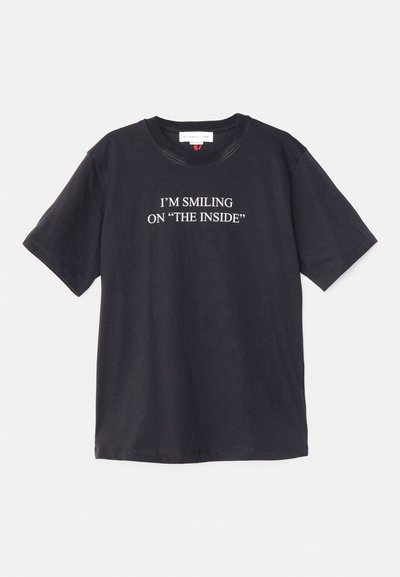 Svart bomull T-skjorte med korte ermer, med teksten "JEG SMILER PÅ INNSIDEN" trykket i hvitt på fronten.
