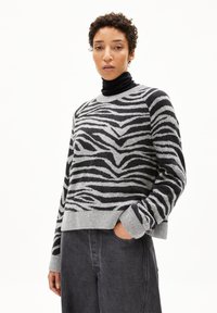Gestreifter Pullover in Grau und Schwarz aus einem weichen Strick, mit Rundhalsausschnitt und gerippten Bündchen, kombiniert mit dunkelgrauen, lässig geschnittenen Hose.