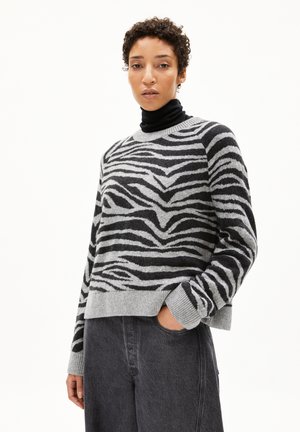 Pull gris et noir à rayures en tricot doux, avec un col ras du cou et des poignets côtelés, associé à un pantalon ample gris foncé.