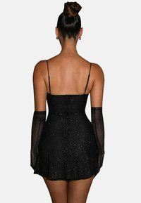 Robe noire courte avec des bretelles fines, jupe évasée et gants transparents. Le tissu présente des paillettes subtiles et une texture lisse, rehaussant son élégance.