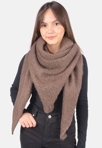 Braunes dreieckiges Halstuch aus weichem, strukturiertem Material, locker um den Hals gelegt, mit fransigen Rändern, kombiniert mit einem schwarzen Oberteil und einer schwarzen Hose.