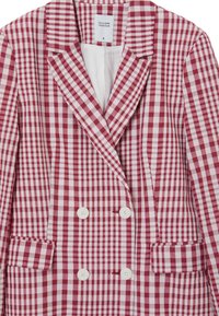Blazer doppiopetto a quadri bianchi e rossi con revers, due tasche frontali e bottoni bianchi. Tessuto di cotone testurizzato.