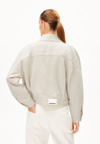 Beige verkürzte Jacke mit einer weichen Textur, oversized Passform und breitem Kragen. Sie verfügt über ein Rückenlabel und stylishe, geknöpfte Ärmel.