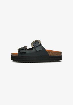 Black slide sandals with two adjustable buckles, cork footbed, textured detailing on buckles, and a thick, ridged rubber sole.