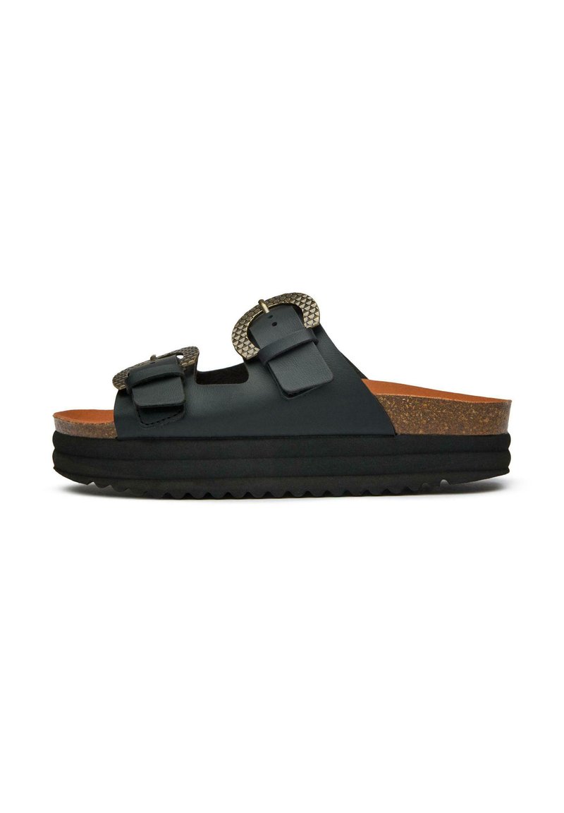 Black slide sandals with two adjustable buckles, cork footbed, textured detailing on buckles, and a thick, ridged rubber sole.
