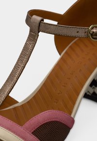 Ροζ και καφέ παπούτσι με μεταλλικό μπρονζέ λουράκι αστραγάλου, υφασμάτινη επιφάνεια με υφή, λείο δέρμα και καφέ ενδιάμεση σόλα με ανάγλυφη υφή.