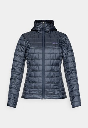 Mornarska izolirana jakna s prošivenim uzorkom, patentnim zatvaračem preko cijele prednje strane, kapuljačom i logotipom Patagonije na lijevoj strani prsa. Glatka, sjajna tekstura tkanine.