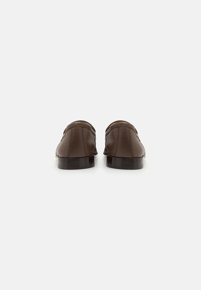 Chaussures en cuir marron avec une texture lisse, un design à bout arrondi et un talon bas. Présente des coutures minimales et aucun accent saillant.