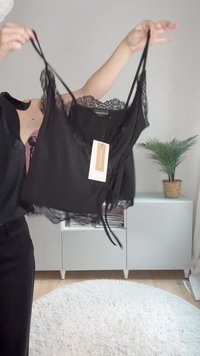Svart cami-top med blondekant, justerbare spaghettistropper og en knyttedetalj foran. Kommer med en merkeetikett festet.