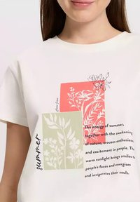 Biała koszulka z krótkim rękawem z kwiatowymi wzorami w koralowych i zielonych prostokątach, z napisem "latem" i cytatem nadrukowanym poniżej.