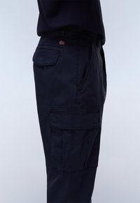 Navy cargo pants made of soft, durable fabric. Features multiple pockets, a patch pocket on the leg, and a small brand emblem.