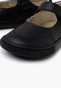 Zapatos Mary Jane de cuero negro con puntera redondeada, parte superior texturizada y correa de Velcro. Presentan una plantilla acolchada y suela de goma.