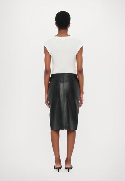 White sleeveless top with a round neckline paired with a black leather pencil skirt featuring back pockets and a high waist design.