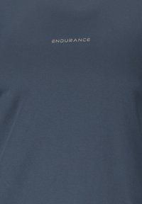T-shirt de sport bleu foncé avec le mot « ENDURANCE » imprimé en petites lettres claires sur le haut de la poitrine.