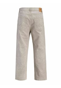 Jean beige à jambes larges avec deux poches arrière et passants pour ceinture, arborant une petite étiquette de marque en cuir marron sur la ceinture.