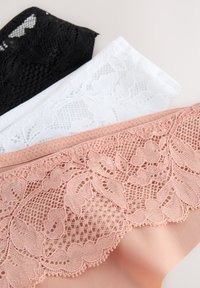 Tre paia di biancheria intima con bordi in pizzo nei colori nero, bianco e pesca. Il modello pesca presenta una fascia in pizzo floreale dettagliata lungo il bordo superiore.