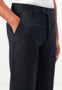Dark navy dress pants with a subtle check pattern, made of a lightweight fabric. Features side pockets and a button closure.