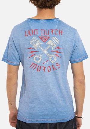 Homme portant un t-shirt bleu clair avec le texte rouge « Von Dutch Motors 1929 » et un graphisme de pistons croisés dans le dos.