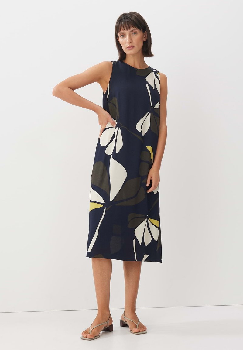 Marineblaues ärmelloses Kleid mit großem weißen und grünen Blumenmuster. Knielang, lockere Passform, aus leichtem Stoff. Enthält Seitentaschen.