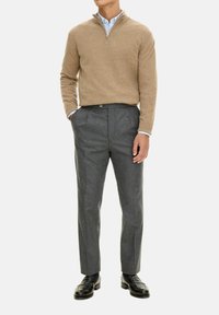 Beige gebreide trui met een kwart ritssluiting, gecombineerd met grijze op maat gemaakte broek en zwarte instappers, minimale textuur en klassieke pasvorm.