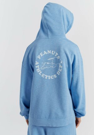 Felpa con cappuccio azzurro chiaro dalla vestibilità comoda. Sul retro presenta una scritta grafica bianca "PEANUTS ATHLETICS DEPT" e un disegno a fumetti. Texture morbida.