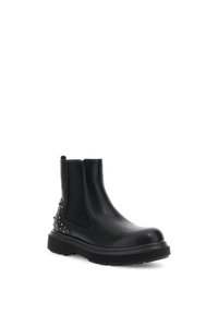Botín Chelsea de cuero negro con lados elásticos, suela de goma texturizada y acentos de tachuelas en el talón, con un diseño de puntera redondeada y elegante.