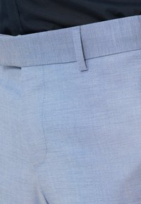 Šviesiai mėlyni kelnių su lygiu paviršiumi, su plokščiu priekiniu pjūviu ir standartiniu juosmeniu. Diskretiški siuvinėjimo elementai šone.