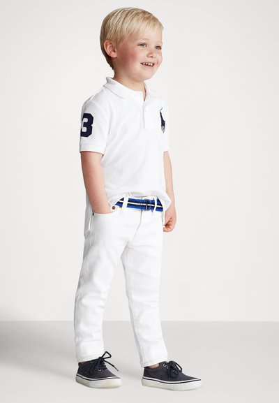 Biela polokošeľa s námorníckym logom a číslom 3, biele rifle a námornícke tenisky. Súčasťou je pás s modrými pruhmi, hladká látka a priliehavý strih.