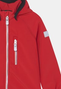 Veste rouge avec capuche, dotée d'une doublure contrastante noire, de fermetures éclair argentées et d'un petit étiquette de marque grise sur la manche. Texture lisse.