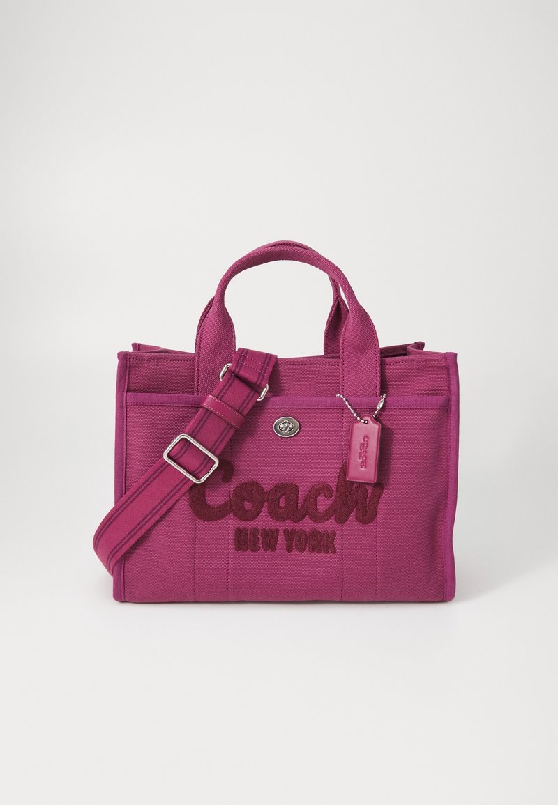 Różowa torebka z płótna z haftowanym logo "Coach New York", podwójnymi uchwytami, regulowanym paskiem i małą metką z logo.