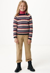 Pestrý pruhovaný svetr v růžové, námořnické a krémové barvě; spárován s béžovými kalhotami a černými šněrovacími botami. Hladká textura, volný střih.