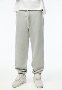 Grijze sweatpants met een relaxte fit, een koord in de taille, zijzakken en elastische boorden, gecombineerd met witte sneakers.