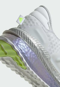 Białe buty sportowe z teksturowanym cholewką, srebrną podeszwą środkową i przezroczystymi fioletowymi akcentami. Posiadają podeszwę z limonkowym motywem i metkę z logo.