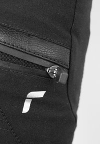 Tela negra con un panel de cuero texturizado y un bolsillo con cremallera. Presenta un diseño de logo blanco en la tela. Superficie suave y herrajes resistentes.