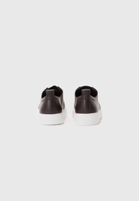 Hnědé kožené tenisky se hladkým povrchem, bílou gumovou podrážkou a poutkem na patě; minimalistický design s elegantním siluetou.