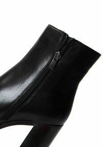 Black leather ankle boot with a side zipper, featuring a textured finish and a chunky heel design. Simple and sleek silhouette.