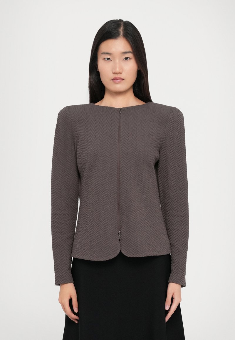 Gray textured jacket with a zigzag pattern, round neckline, and front zipper. Long sleeves and a fitted design.