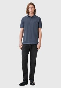 Mörkblå polo t-shirt i bomullsmix, med en tre-knapps placket och korta ärmar. Matchad med svarta slim-fit jeans och svarta skor.