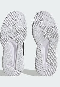Svarta idrottssko-sulor med texturerad vit gummi, med ett zigzag-mönster och tydliga grepp-element. Adidas-logotyp närvarande.