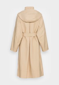 Trench-coat long beige avec pli au dos, capuche attachée, large ceinture et manches longues, vu de dos sur fond blanc.