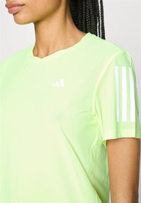 Heren overhemd met korte mouwen in fel neon groen mesh stof. Heeft witte verticale strepen op de linkerschouder en een logo op de borst.