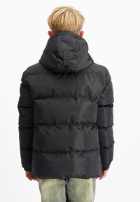 Zwarte pufferjack met capuchon, met een gequilte design en gestreepte structuur. Glad materiaal met een relaxte pasvorm, gezien vanuit de achterkant.