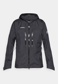 Giacca Mammut nera con cappuccio, multiple tasche con zip, una texture liscia e zip frontale. Progettata per attività all'aperto.