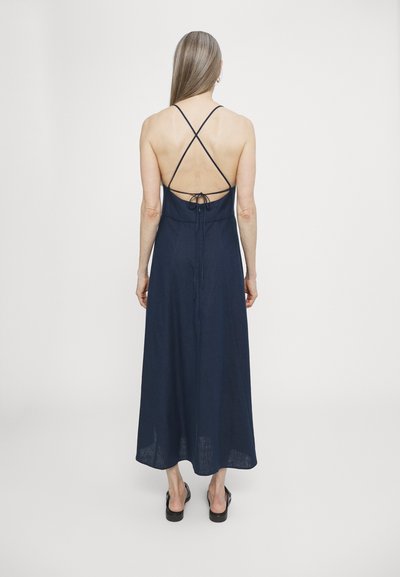 Robe maxi en lin bleu marine avec un design à dos croisé, taille réglable avec lien, et une silhouette fluide qui atteint les chevilles.