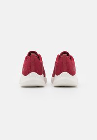 Pair of red athletic sneakers with white soles, shown from the back, featuring mesh fabric and pull tabs on a plain white background.
